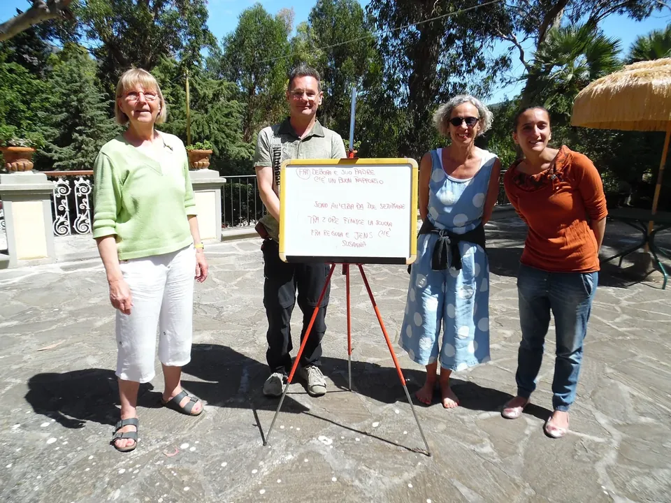Erwachsene neben einer Tafel mit Italienischübungen im Park der Villa Teresa