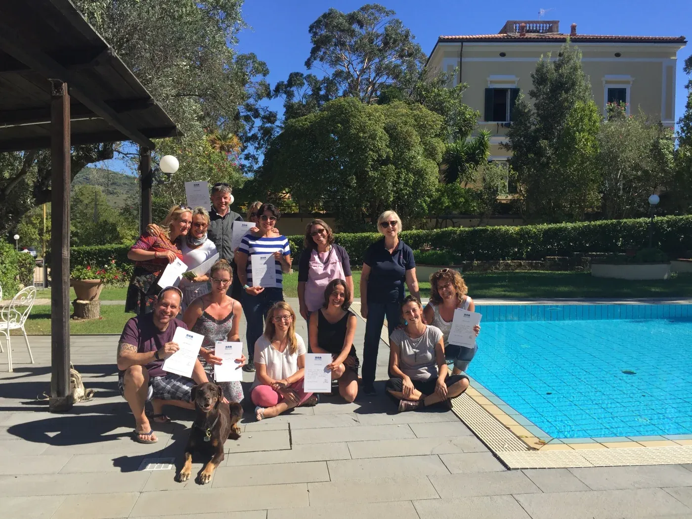 Teilnehmende von ABC ELBA mit ihren Kursbescheinigungen am Pool der Villa Teresa