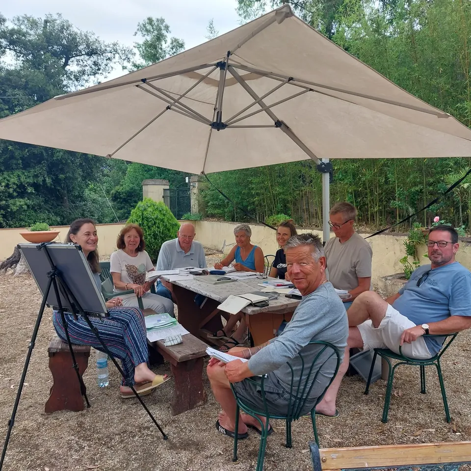 Una clase de adultos con profesora, pizarra y materiales en el parque de Villa Teresa