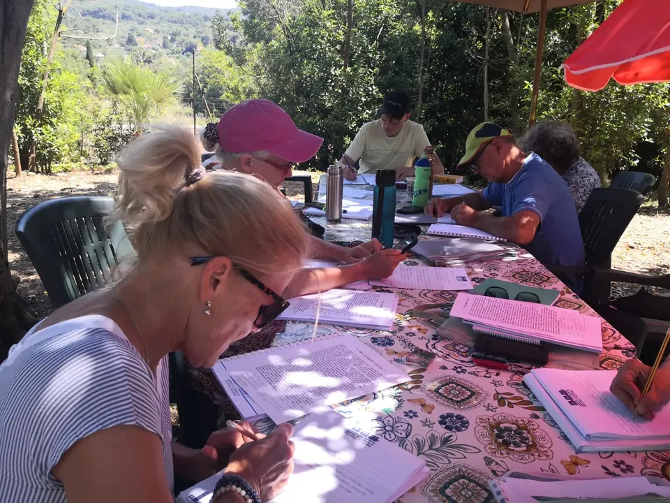 Adults concentrating on written Italian exercises in the gardens of Villa Teresa