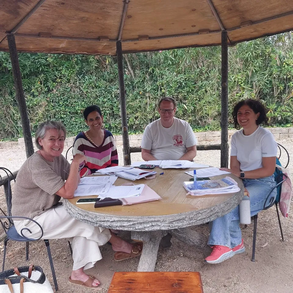 Four adults with course materials around a table in a garden pavilion at Villa Teresa