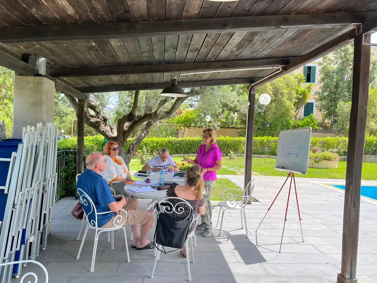 Lehrerin und Erwachsene beim Italienischunterricht am Pool der Villa Teresa
