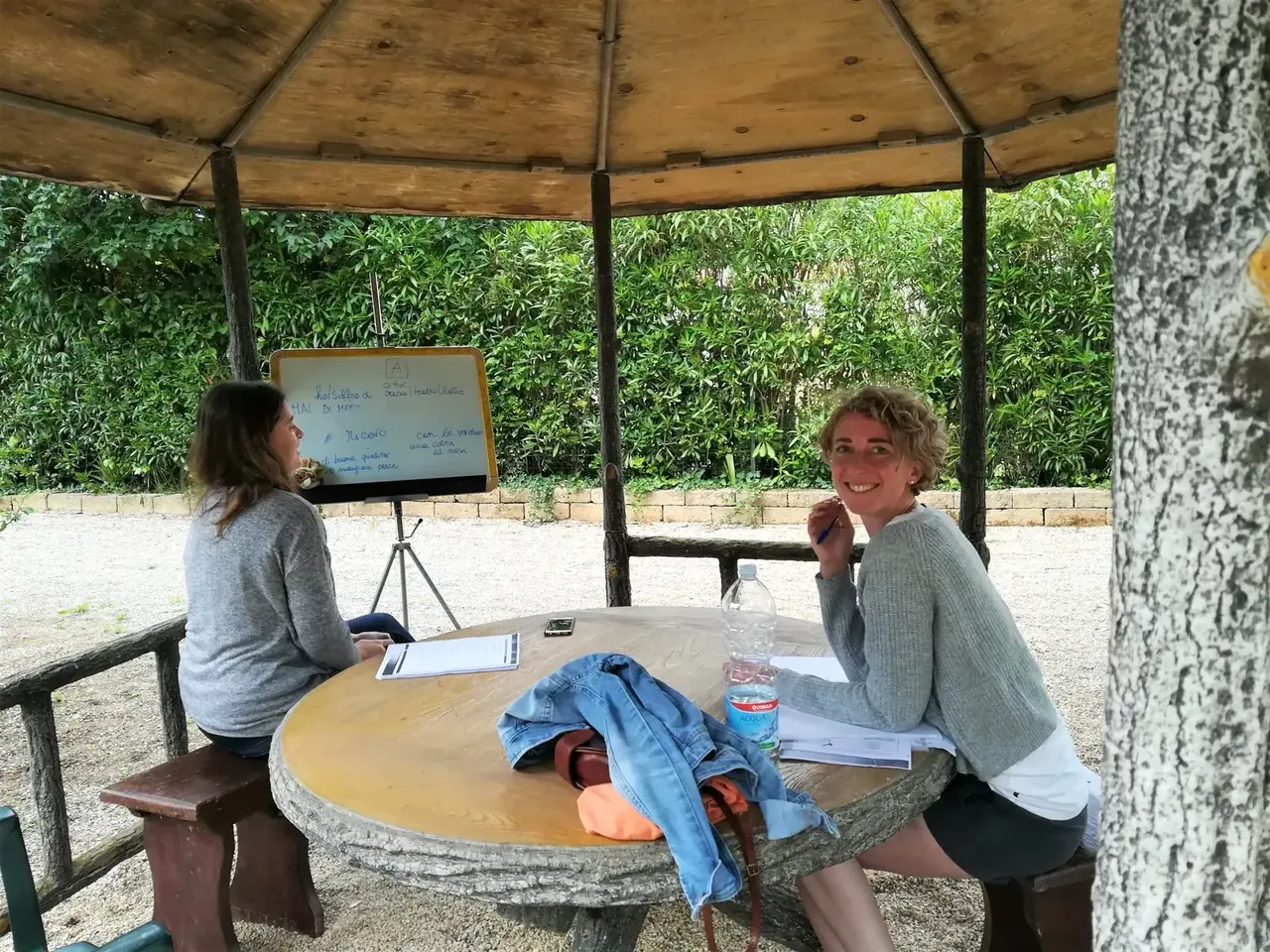 Zwei Personen beim Einzelunterricht an einem Tisch im Gartenpavillon