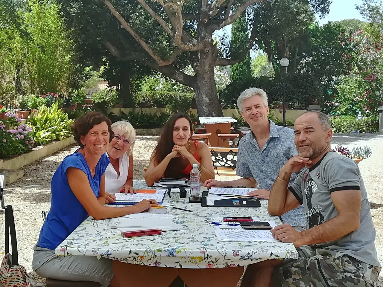 Kleine Gruppe Erwachsener beim Italienischunterricht im Garten