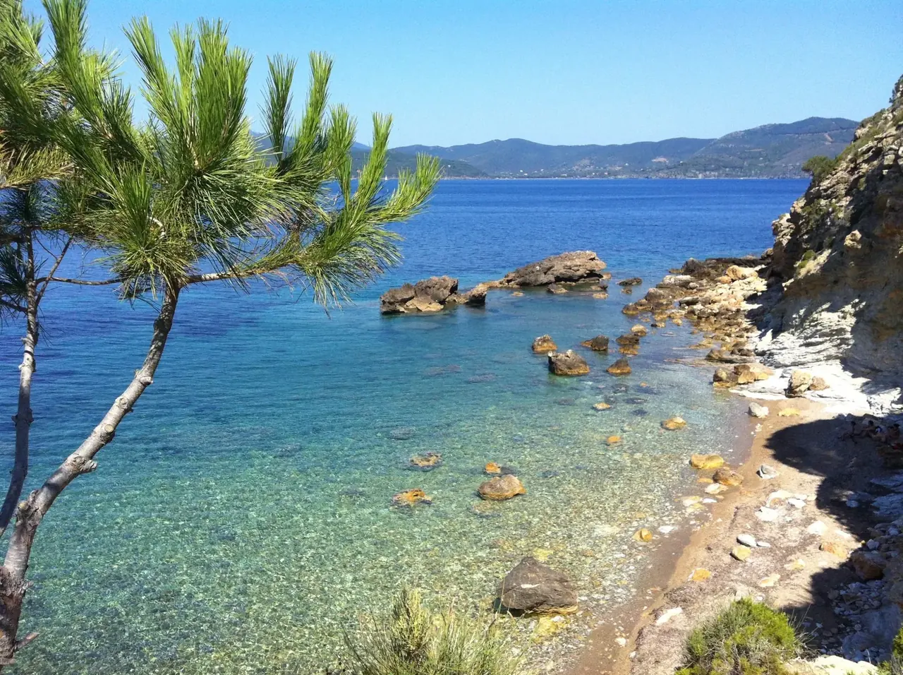 Kleine Bucht mit Strand und Felsen am klaren Meer