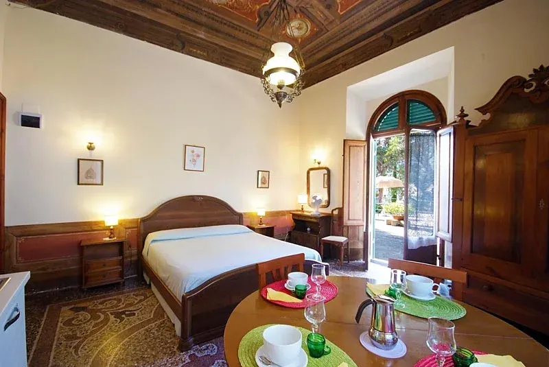 Studio with double bed, dining table and tall windows