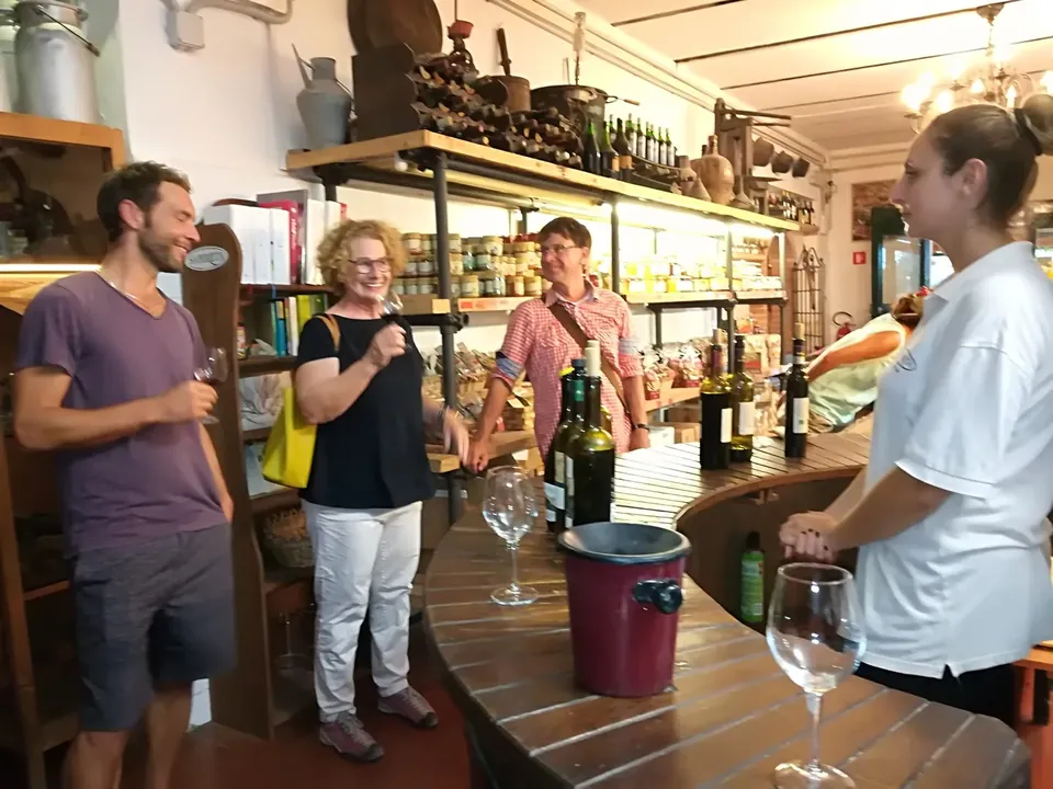Adultos en una cata de vinos, con botellas y copas sobre el mostrador