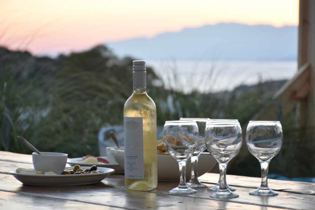 Weinflasche und Gläser auf einer Terrasse mit Meerblick